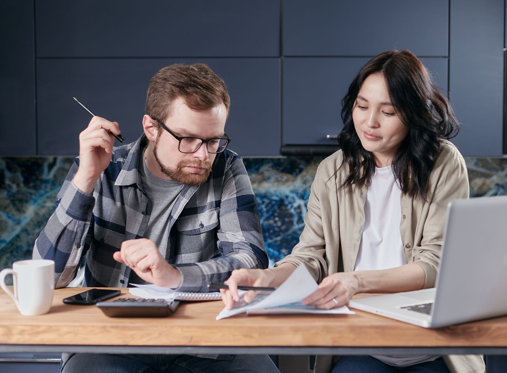 A couple reviewing a paper household budget beside a calculator